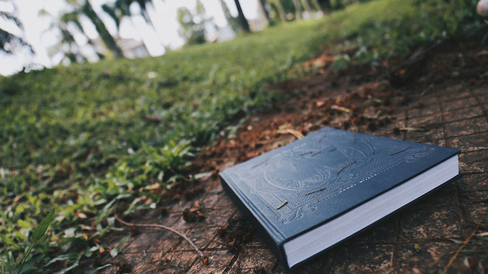 photo of a black book outside near the grass, by Kevin Menajang